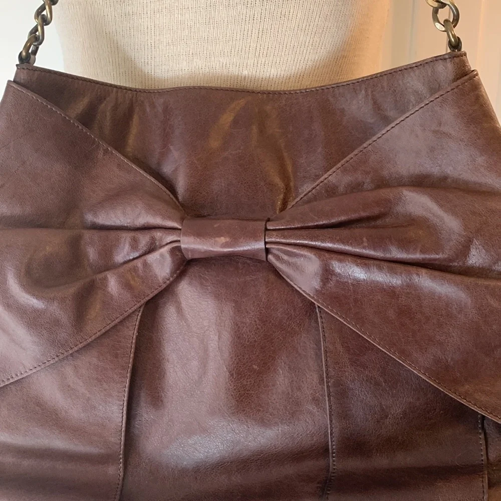 Hobo brown leather purse with bow on front and brass looking chain strap